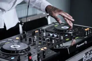 Man with tattoos using pioneer DJ controller.