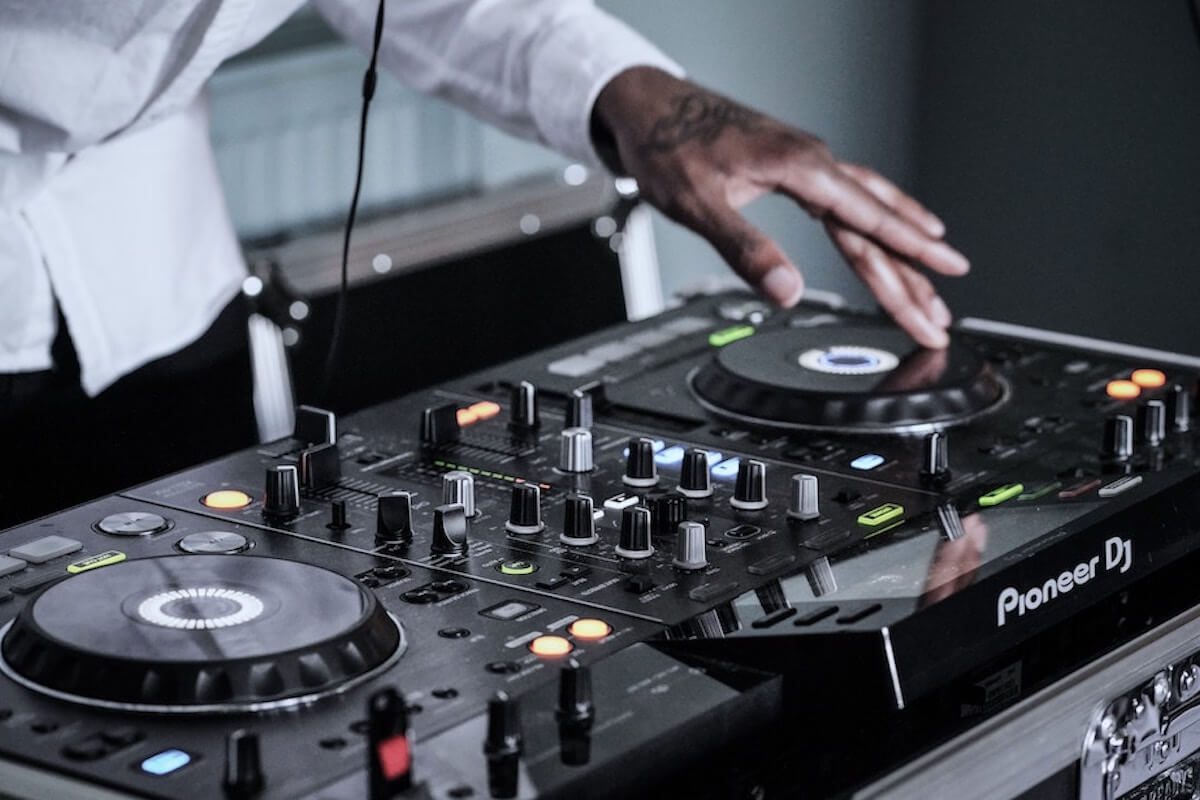 Man with tattoos using pioneer dj controller.