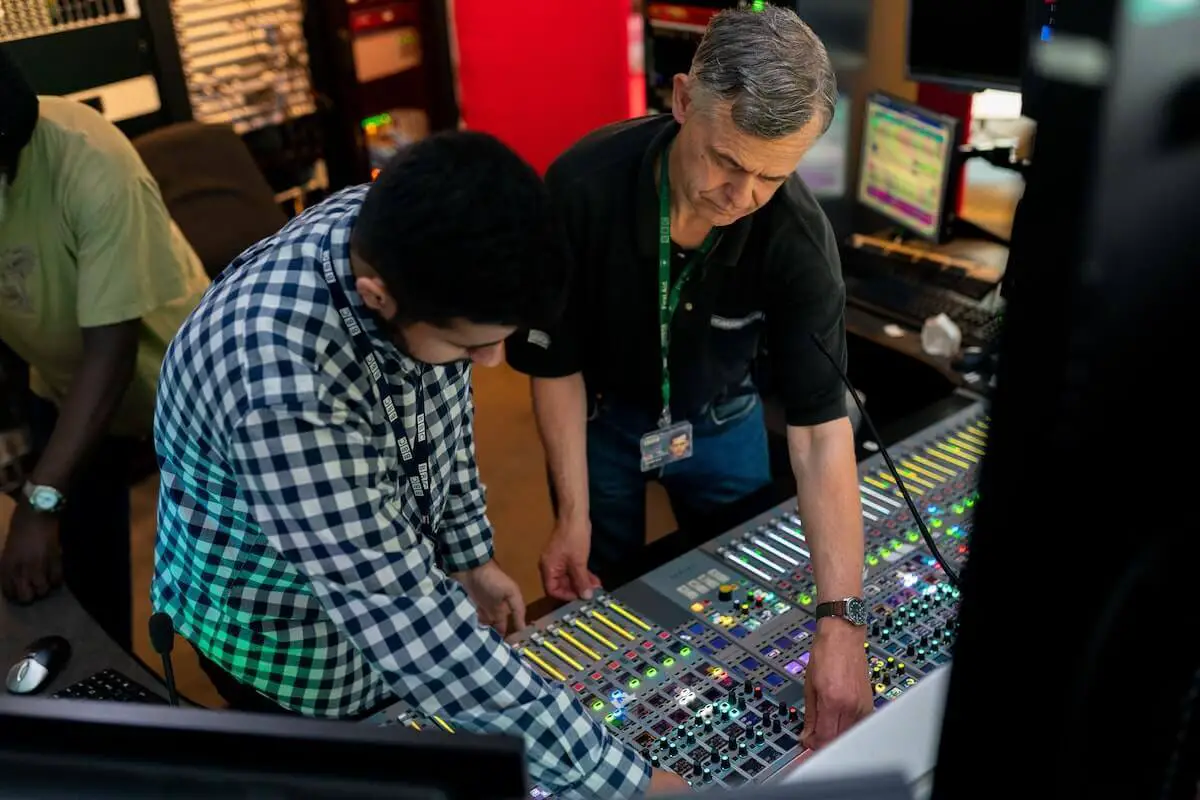 Image of a producer and a sound engineer adjusting mixers. Source: unsplash