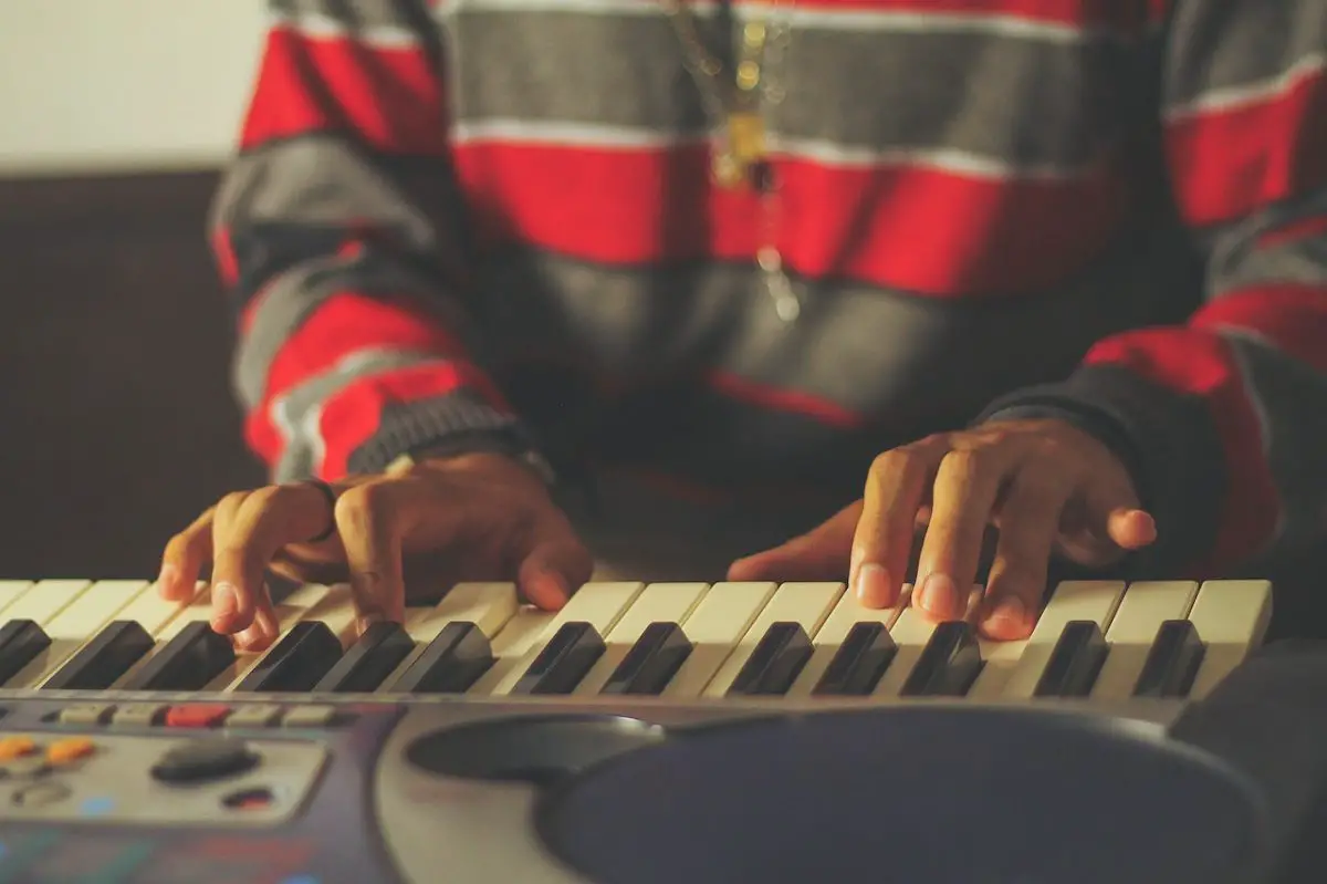 Image of a person playing music using a midi keyboard. Source: gezer amorim, pexels