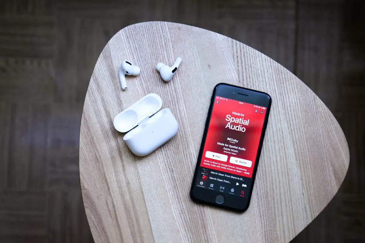 Image of airpods and a black iphone on a table. Source: auguras pipiras, unsplash