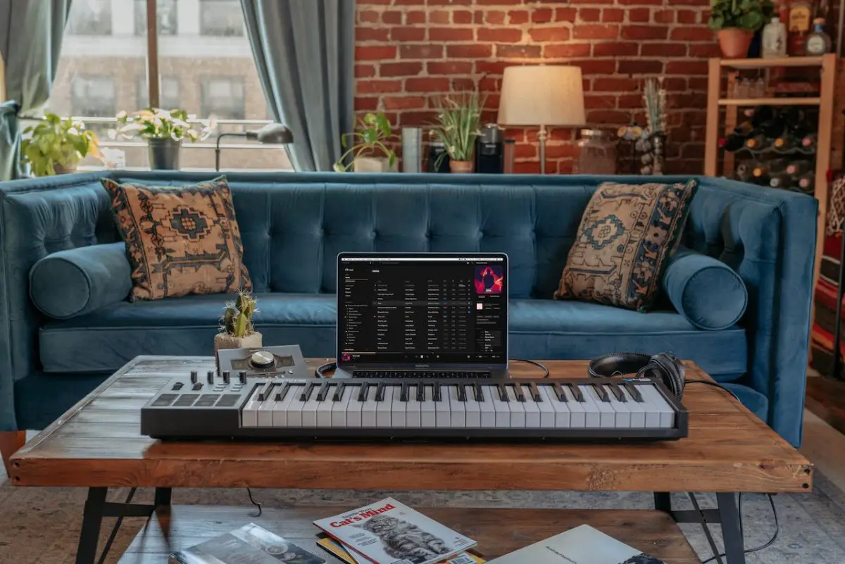 Image of a midi controller on top of a table connected in a laptop. Source: vollume, pexels