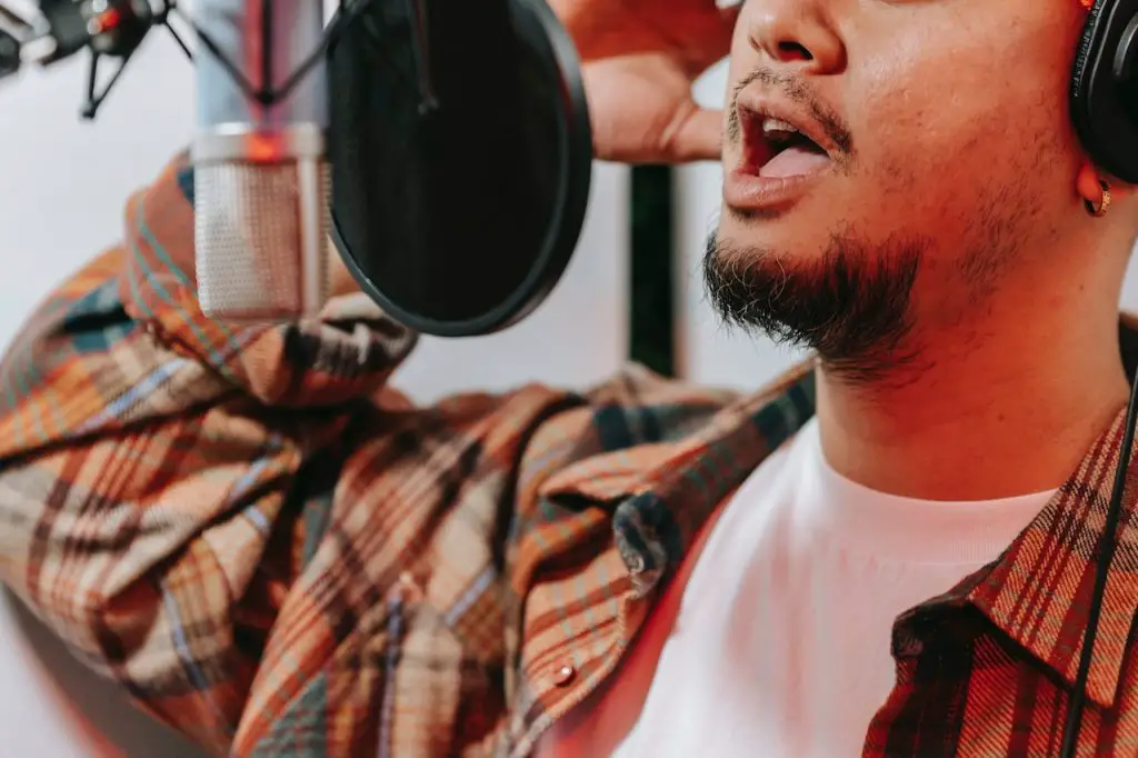 Image of a man recording vocals using a microphone with a pop filter. Source: anna pou, pexels