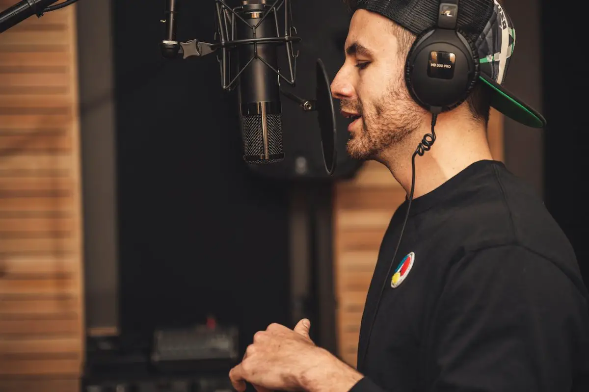 Image of a man wearing headphones while recording vocals using a microphone. Source: brett sayles, pexels