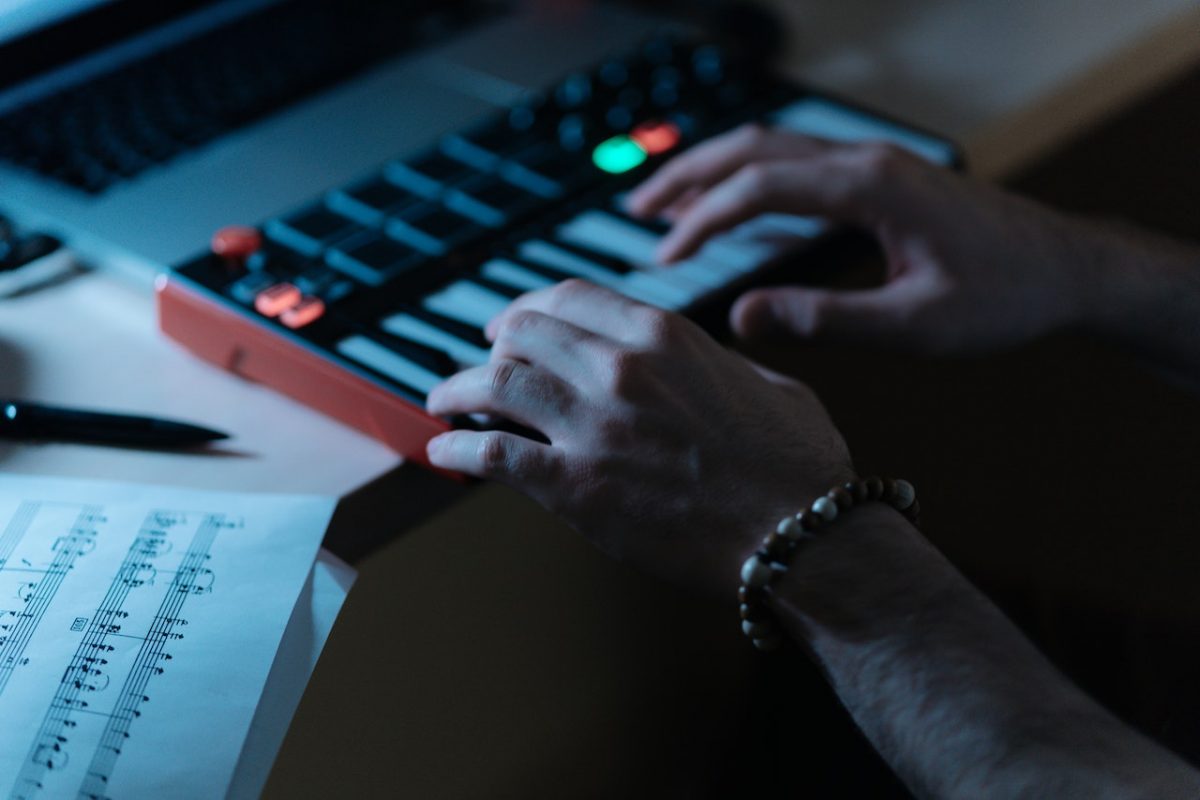 Image of a person using a synthesizer as a midi controller. Source: cottonbro studio, pexels