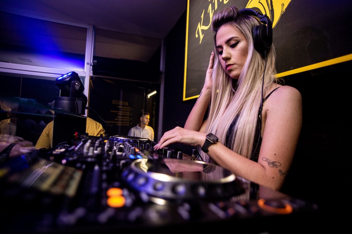 Image of a woman wearing a headphone while playing music using a midi synth. Source: Guto Macedo, Pexels