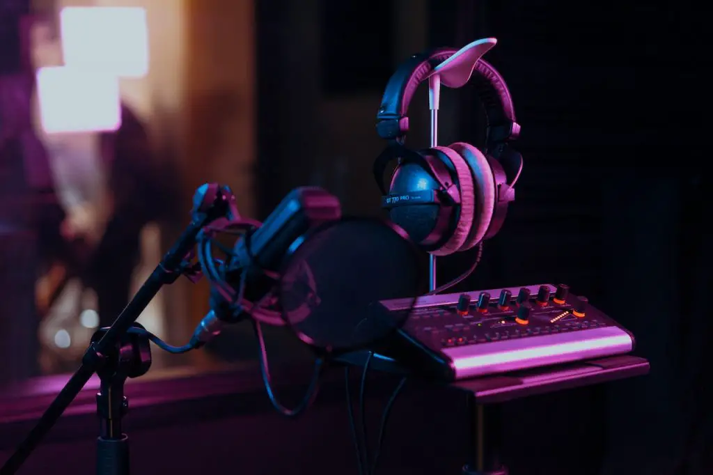 Image of black microphone on a stand with a midi and a black headphone. Source: los muertos crew, pexels