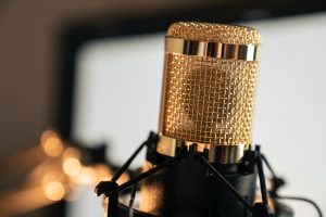 Image of gold colored microphone in a stand. Source: Felipepelaquim, Pexels
