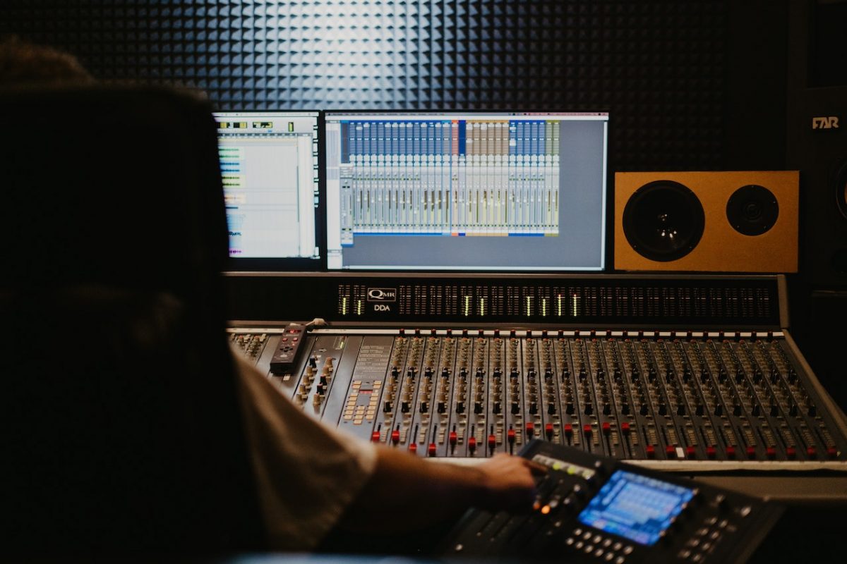 Image of someone sitting in front of a computer and a midi controller with a plugin. Source: Tima Miroshnichenko, Pexels