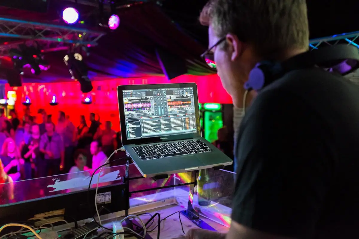 Image of a dj in front of a laptop, while mixing music. Source: pixabay