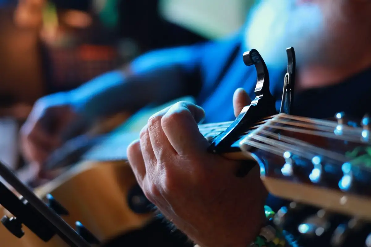 Image of a black capo on a guitar. Source: alexander hamilton, pexels