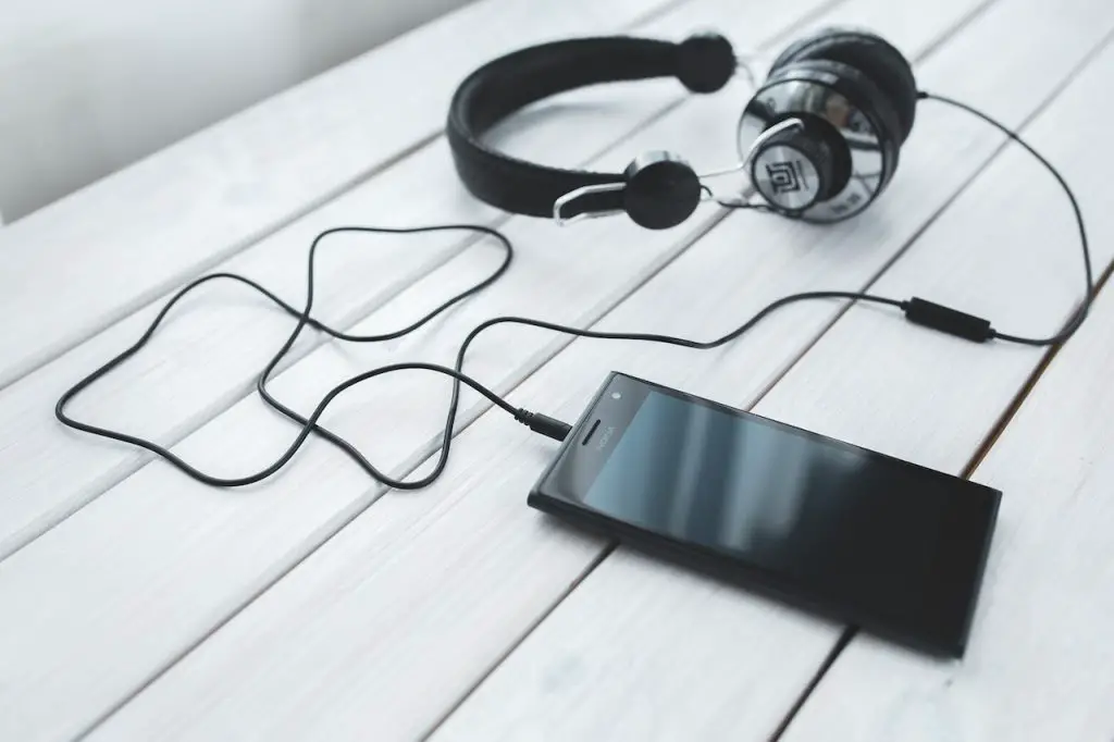 Image of a black wired headphone connected to a mobile phone. Source: kaboompics com, pexels