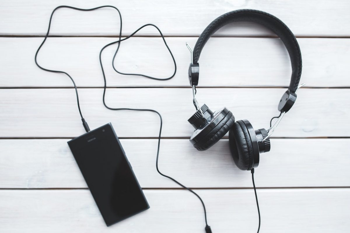 Image of a black wired headphones connected to a mobile phone. Source: kaboompics com, pexels