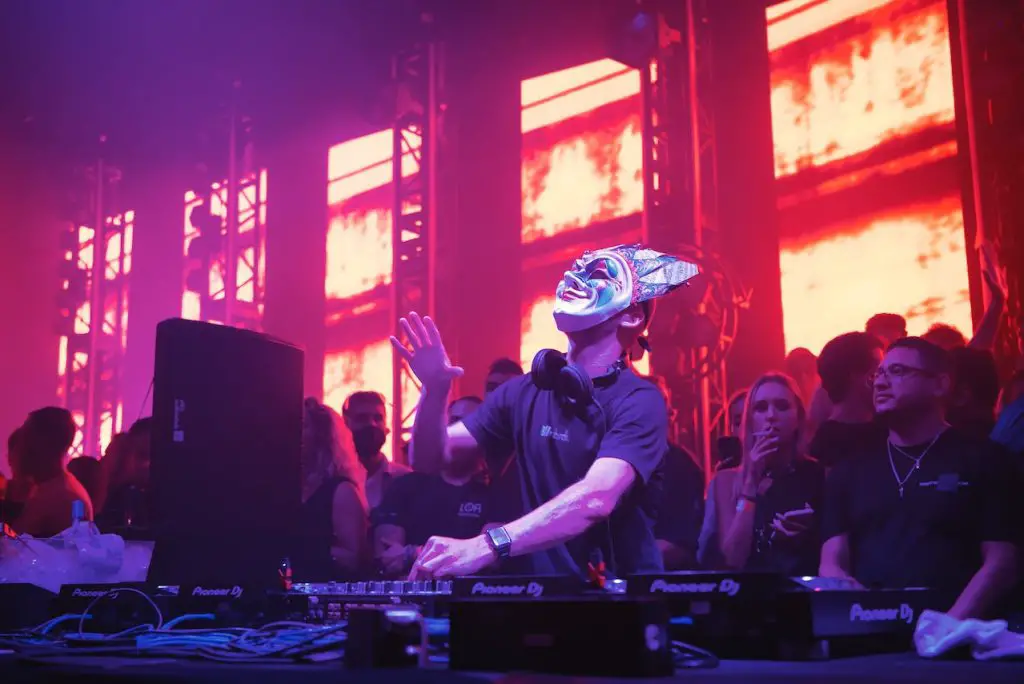 Image of a dj wearing a mask while mixing music. Source: odin reyna, pexels