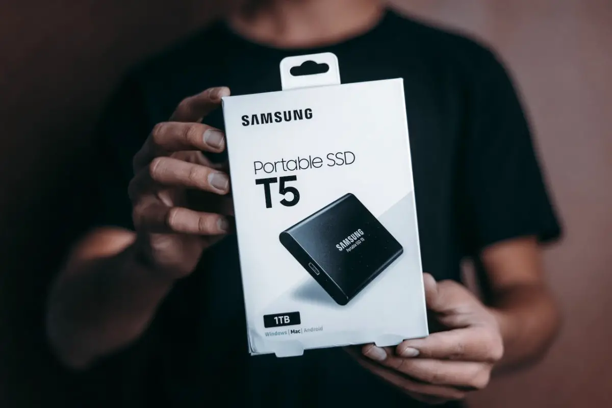 Image of a man holding a samsung portable ssd. Source: luis quintero, pexels