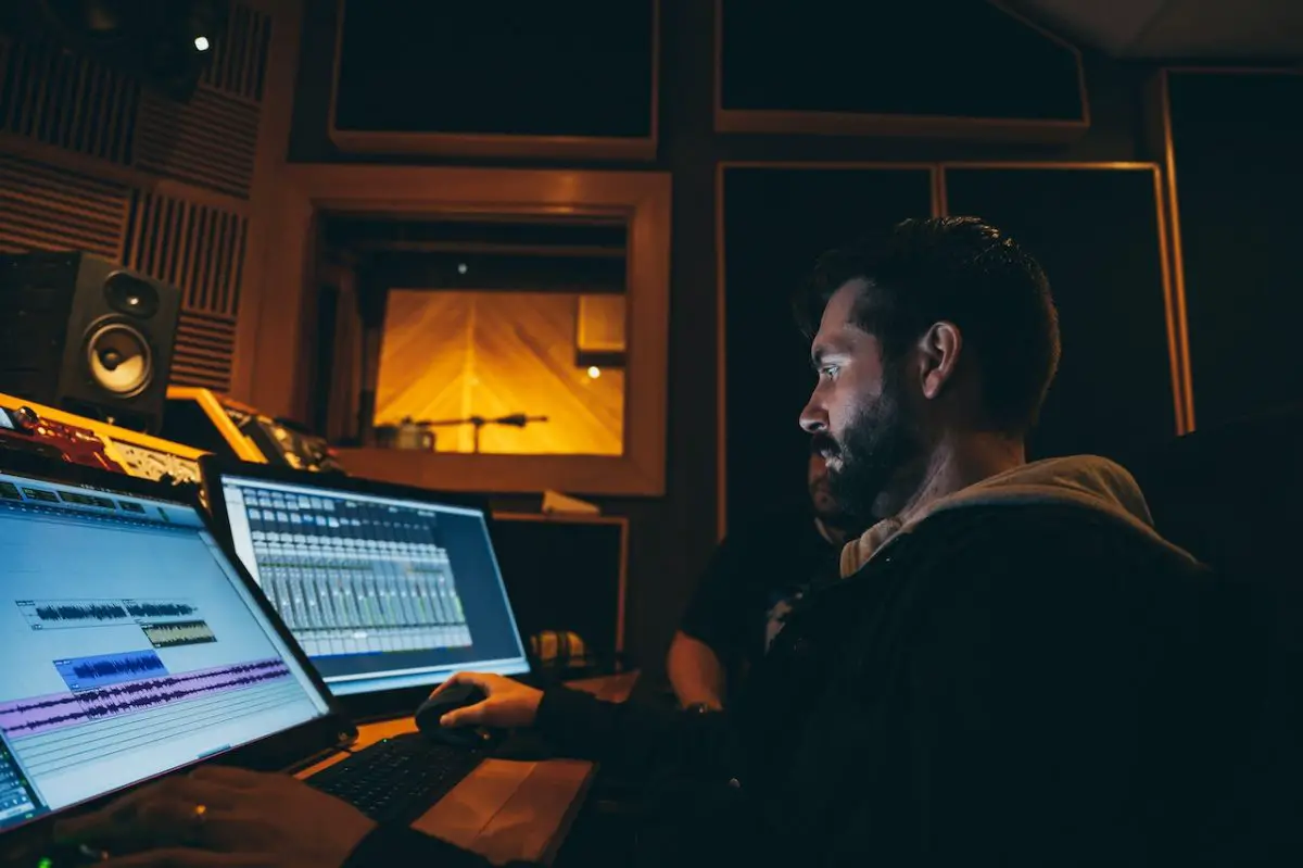 Image of a man in front of a computer inside a recording studio. Source: Brett Sayles Pexels