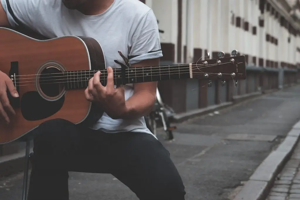 Image of a man playing the guitar with a capo. Source: lachlan ross, pexels