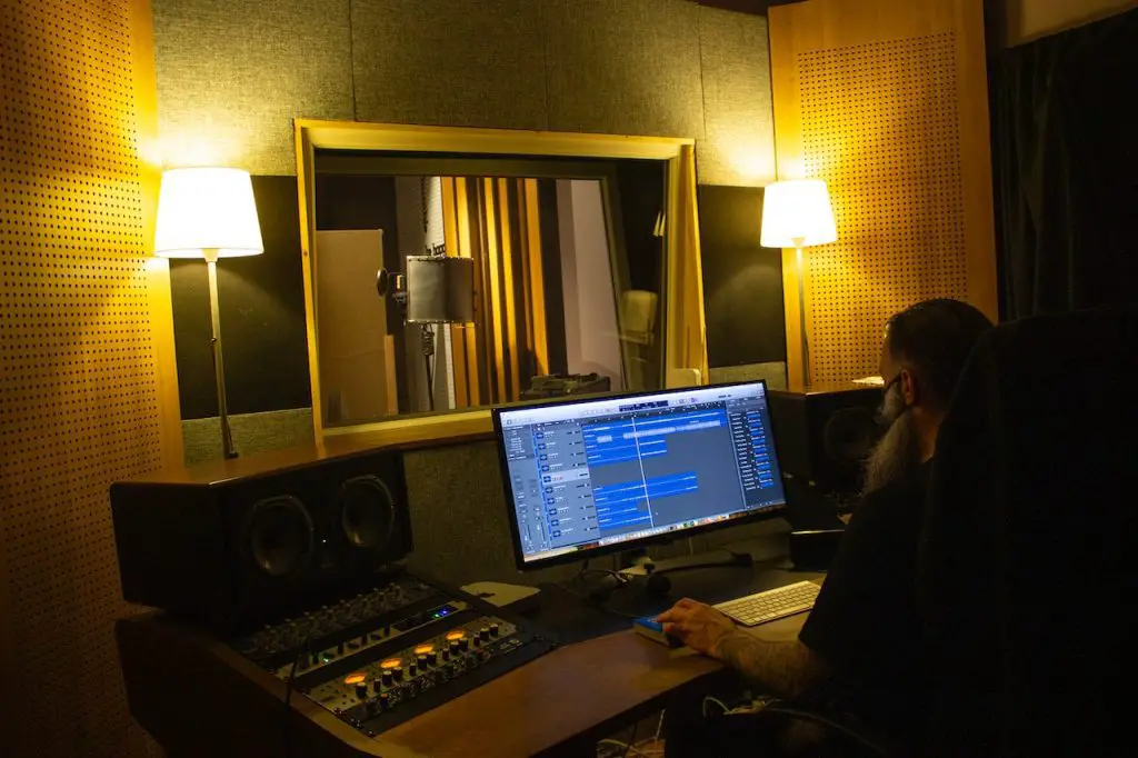 Image of a man with a studio monitor in front of him inside a music studio. Source: do ancan, pexels