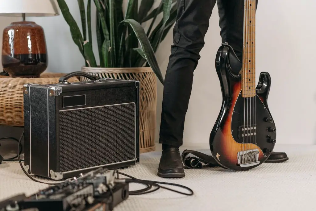 Image of a man with black guitar and amplifier. Source: Pavel Danilyuk, Pexels