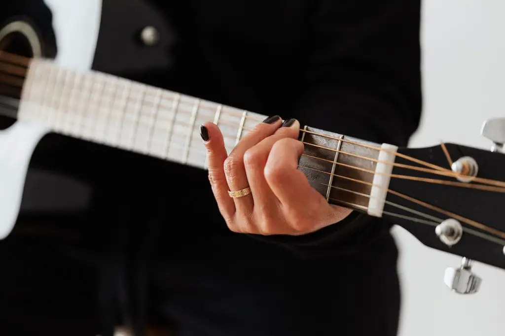 Image of a person in black while playing a guitar. Source: karolina grabowska, pexels
