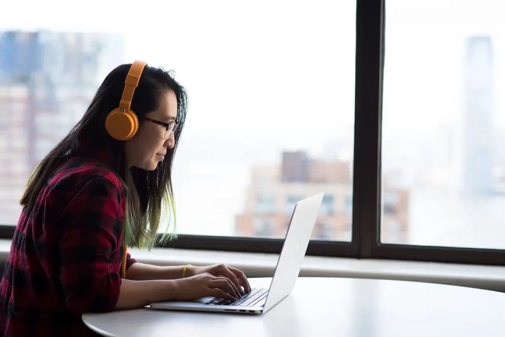 Image of a woman wearing a yellow headphones while working on her laptop. Source: christina morillo, pexels