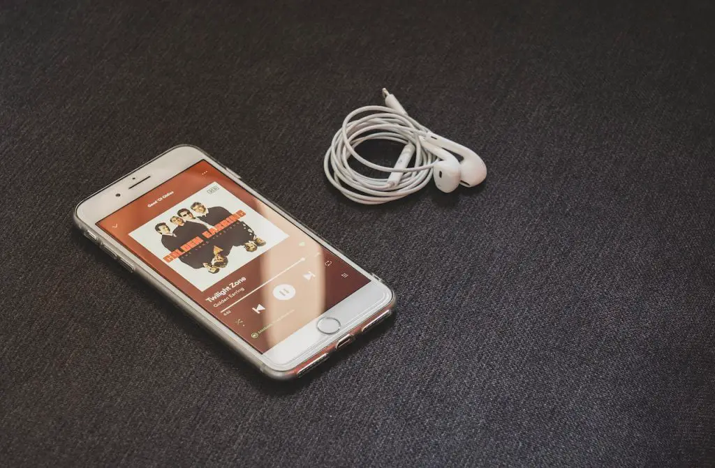 Image of mobile phone while streaming on spotify music with an earphones beside it. Source: castorly stock, pexels