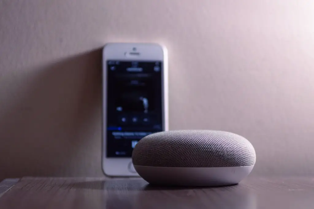 Image of a gray mini bluetooth speaker connected on a mobile phone. Source: caio, pexels