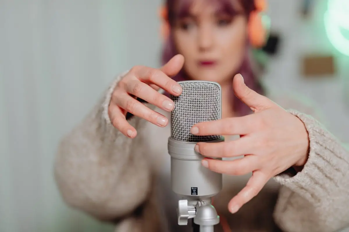 Image of a woman tapping a silver microphone. Source: karolina grabowska, pexels