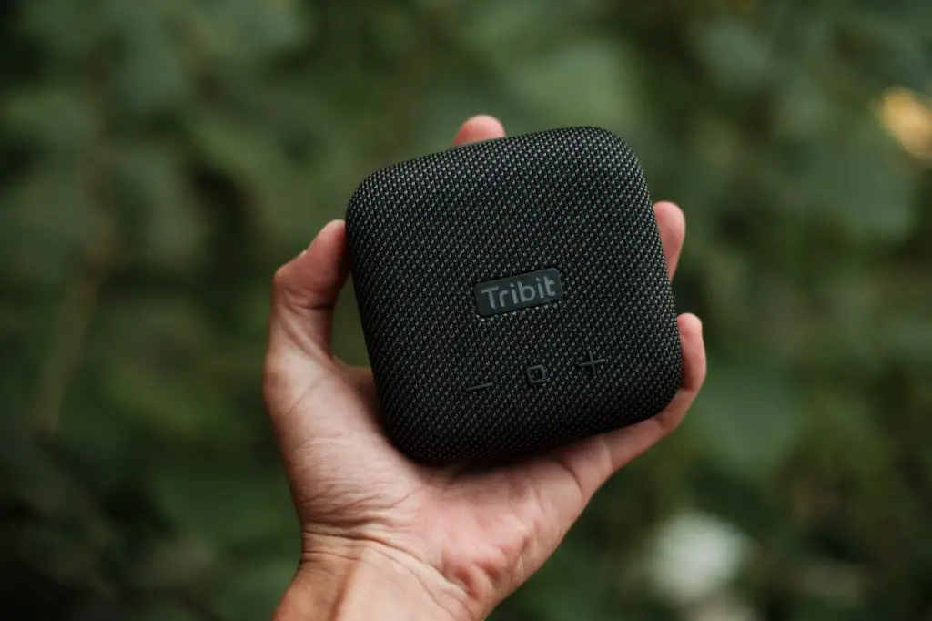 Image of someone holding a black modern portable Bluetooth speaker. Source: Kei Scampa, Pexels