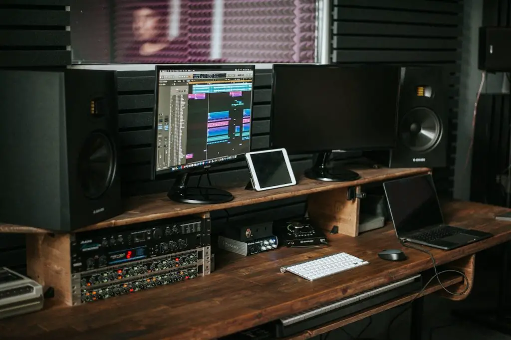 Image of two monitors on a table with an audio mixer. Source: John Wolf, Pexels