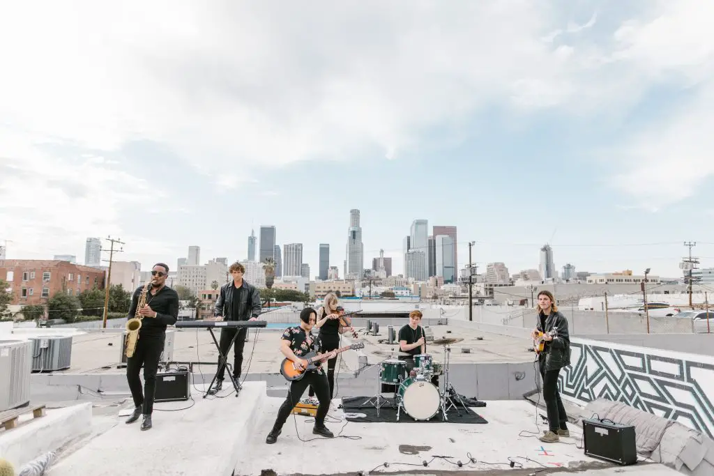 Image of a band playing with their instruments on a rooftop source pexels