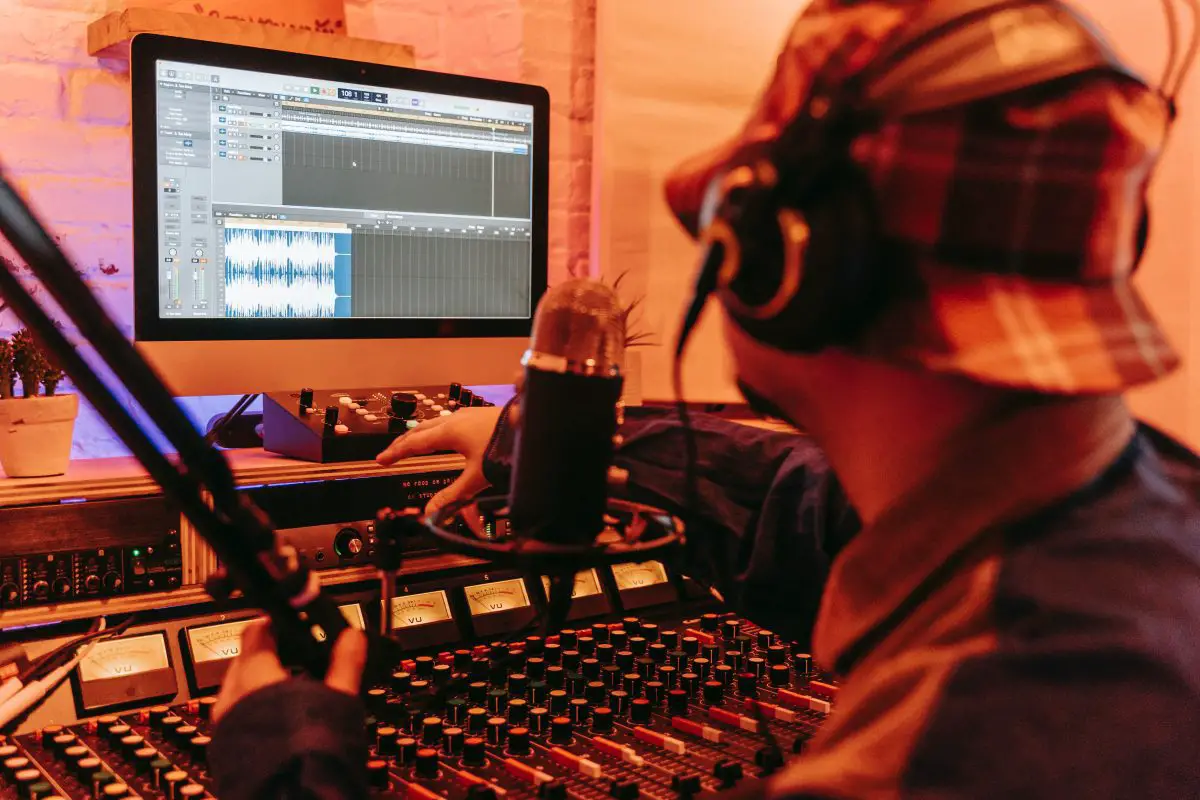 Image of a male producer in front of audio mixer and other audio equipment. Source: unsplash