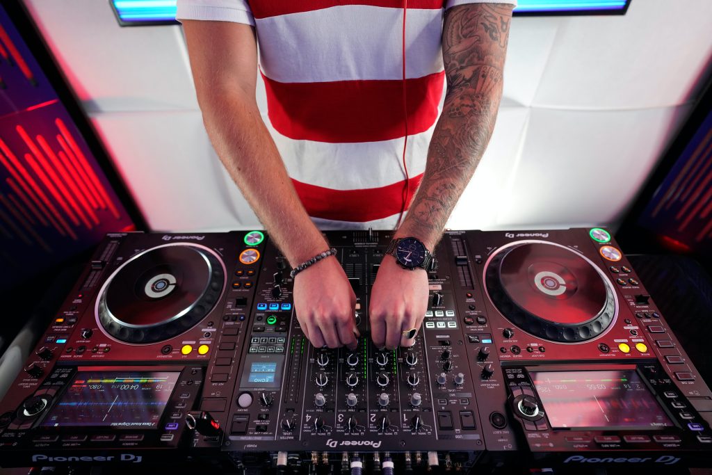 Image of a man in front of an audio mixer. Source: pexels