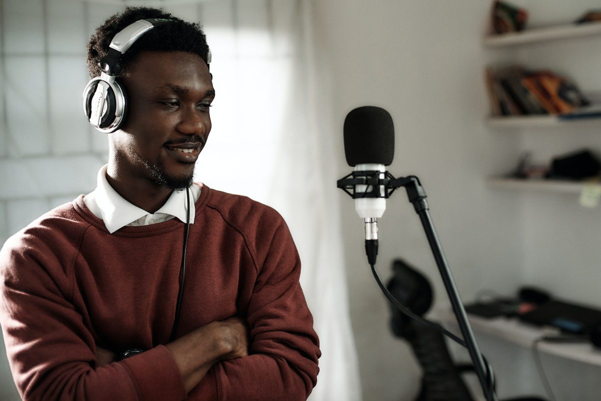 Image of a man with a microphone in front. Source: unsplash