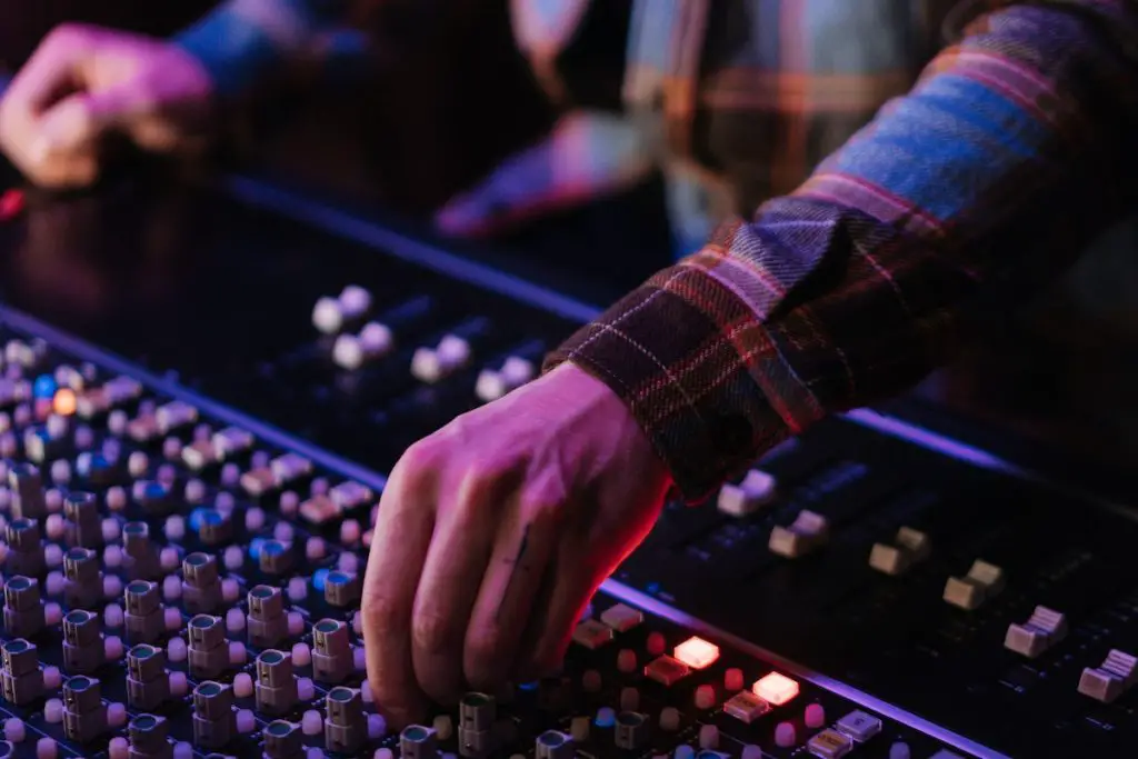 Image of a musician controlling an audio mixer. Source: pexels