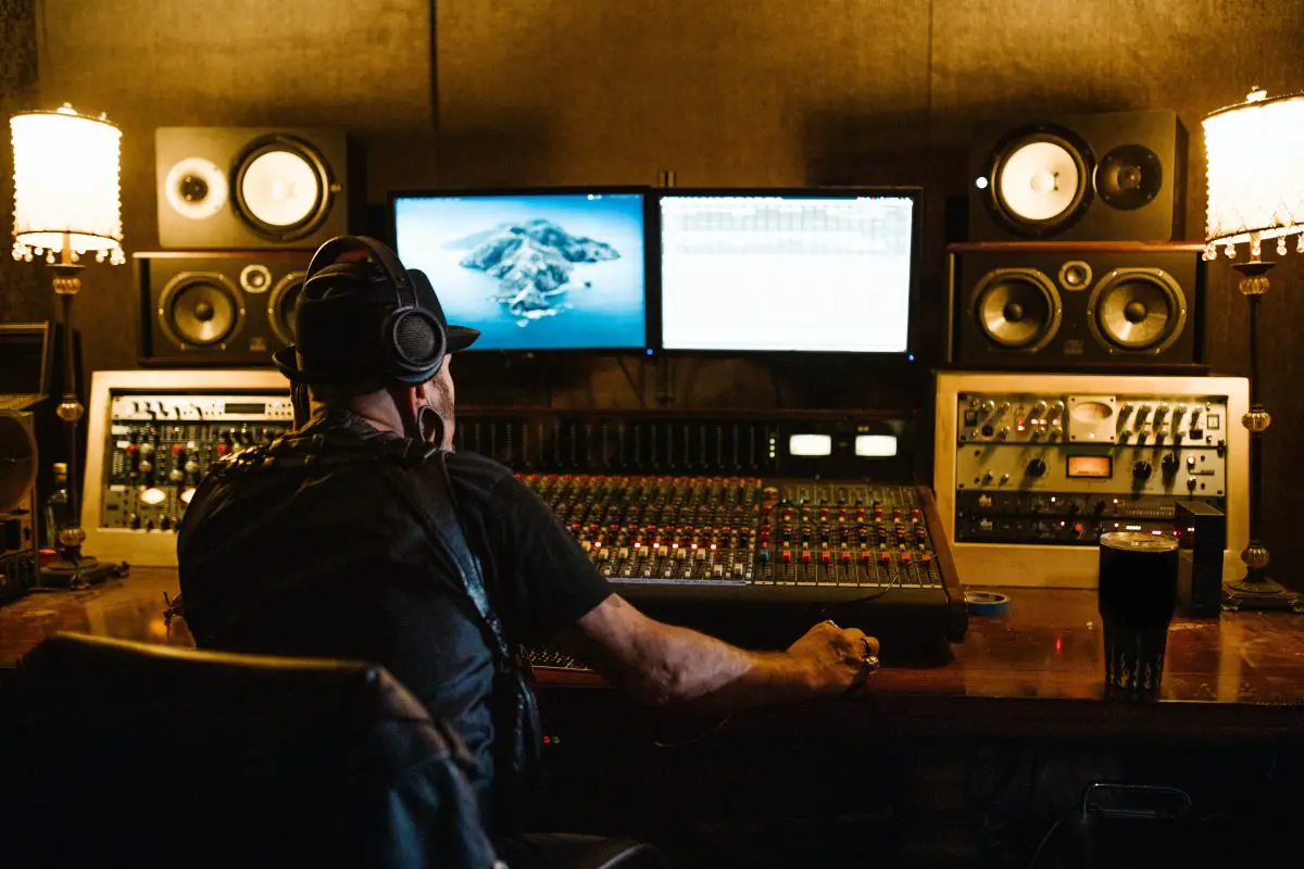 Image of a producer sitting in front of his monitors and audio mixer. Source: pexels