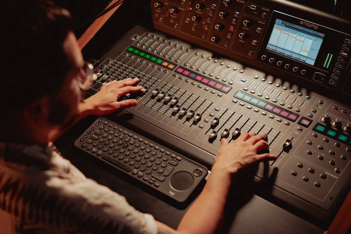 Image of a sound engineer controlling the audio mixer. Source: pexels