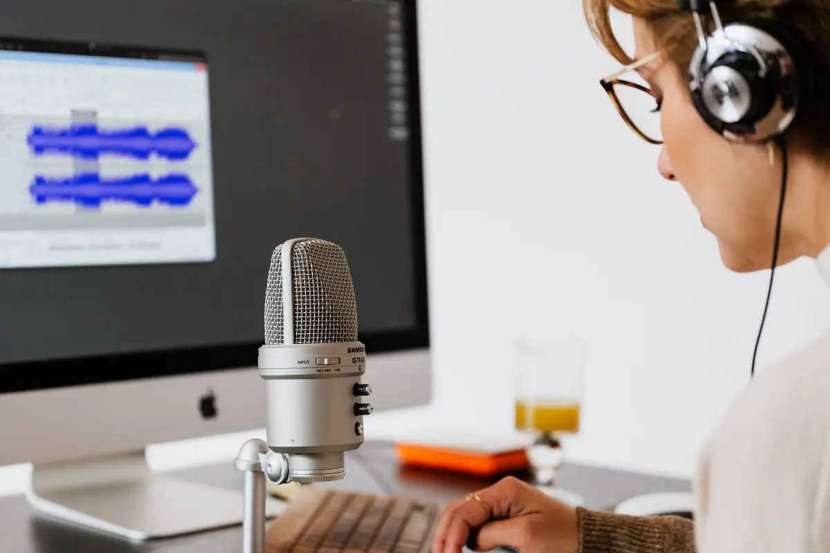 Image of a woman in front of a microphone and monitor. Source: pexels