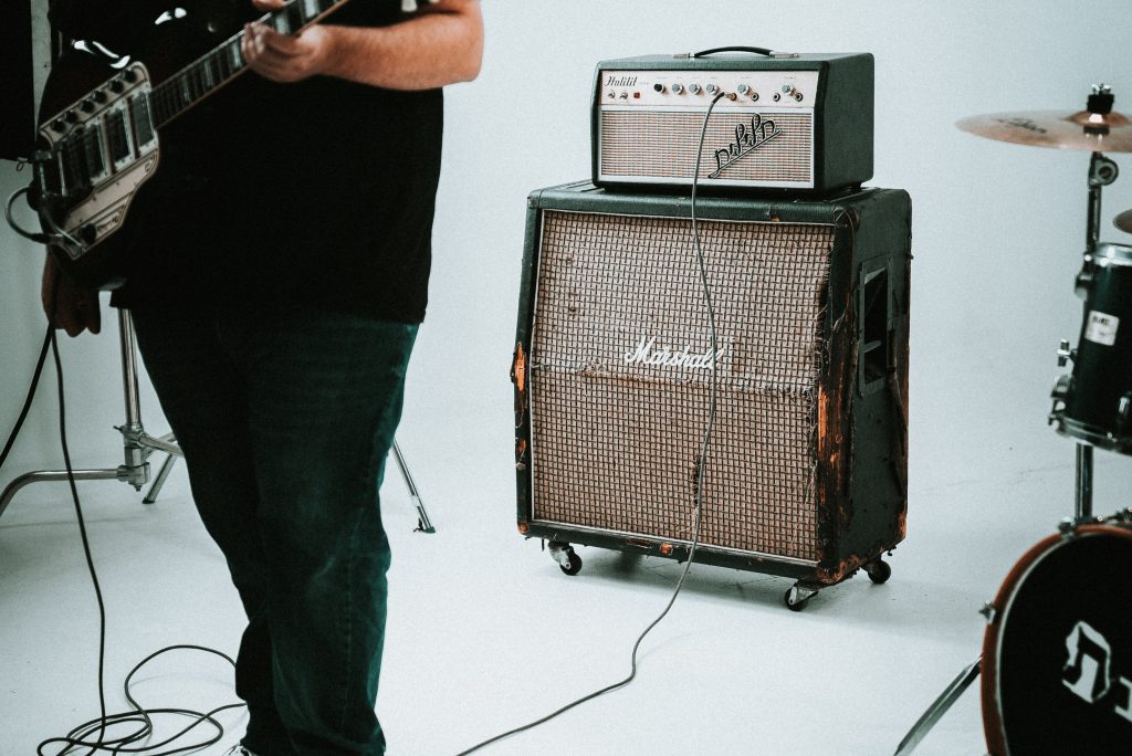 Image of an amplifier and a guitarist source unsplash 1