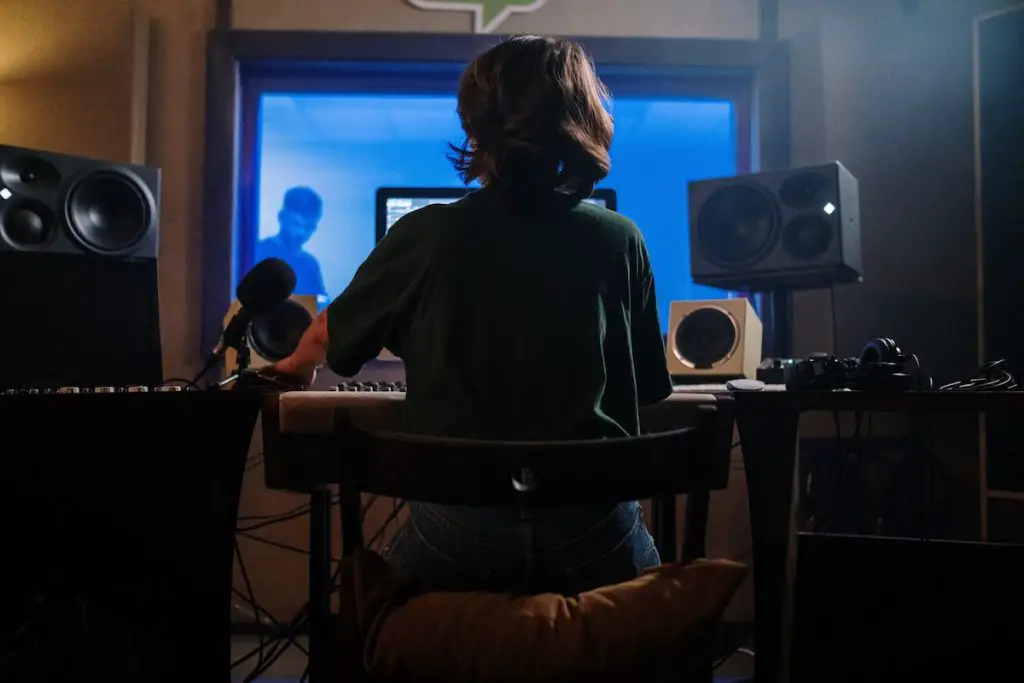 Image of a woman sitting in a studio with monitors and speakers. Source: pexels