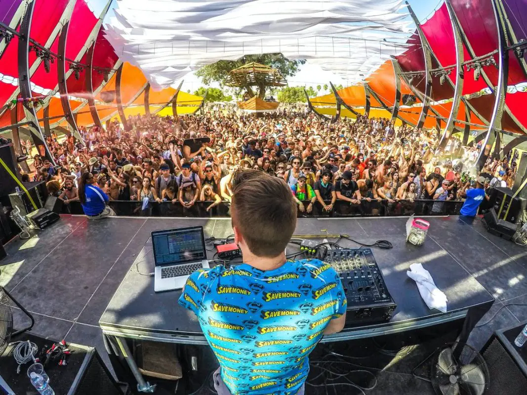 Image of a dj on stage in front of a large crowd. Source: unsplash