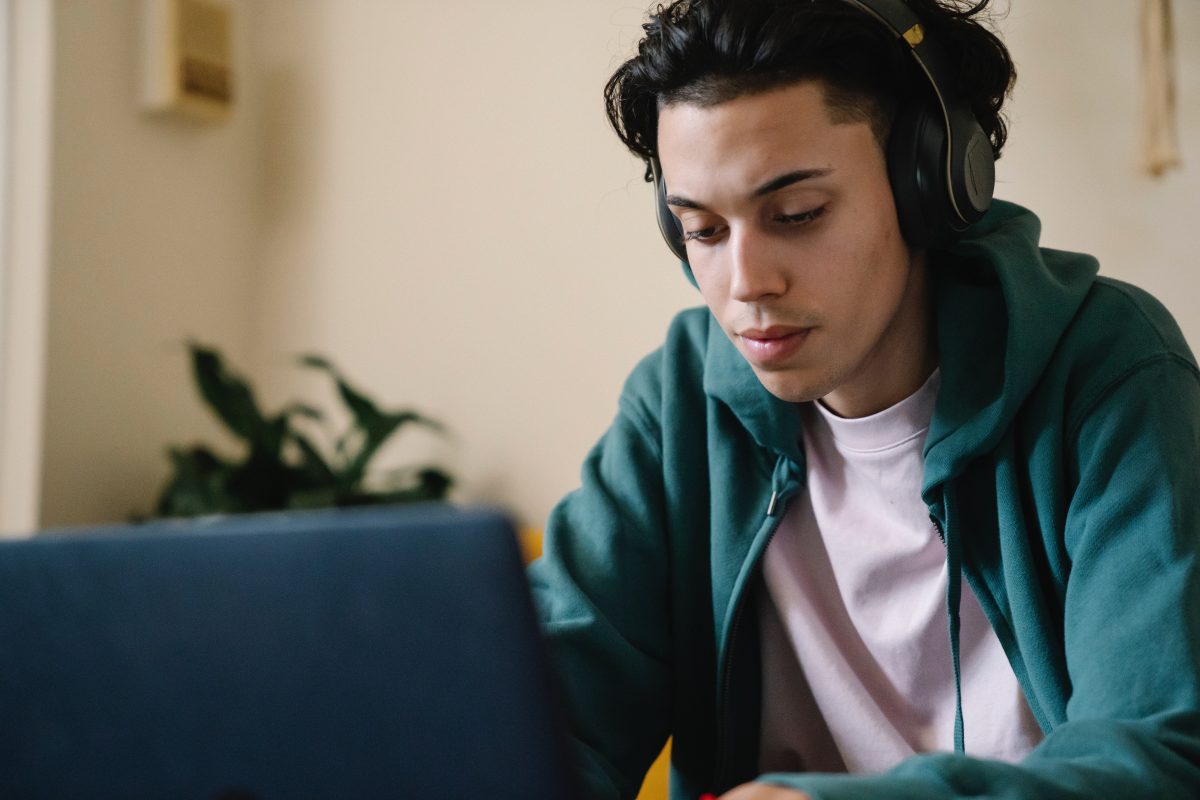 Image of a concentrated man in headphones working on laptop at home. Source: pexels