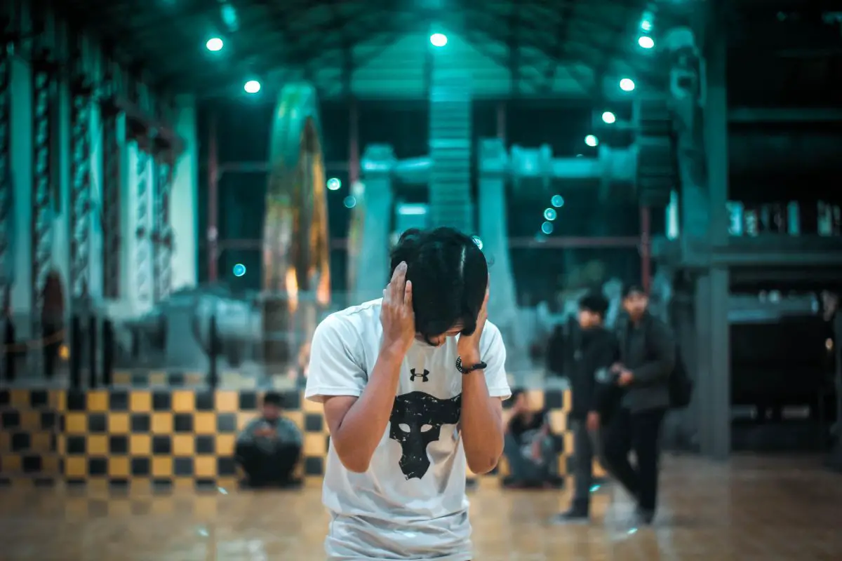 Image of a man in white shirt closing his ears. Source: unsplash