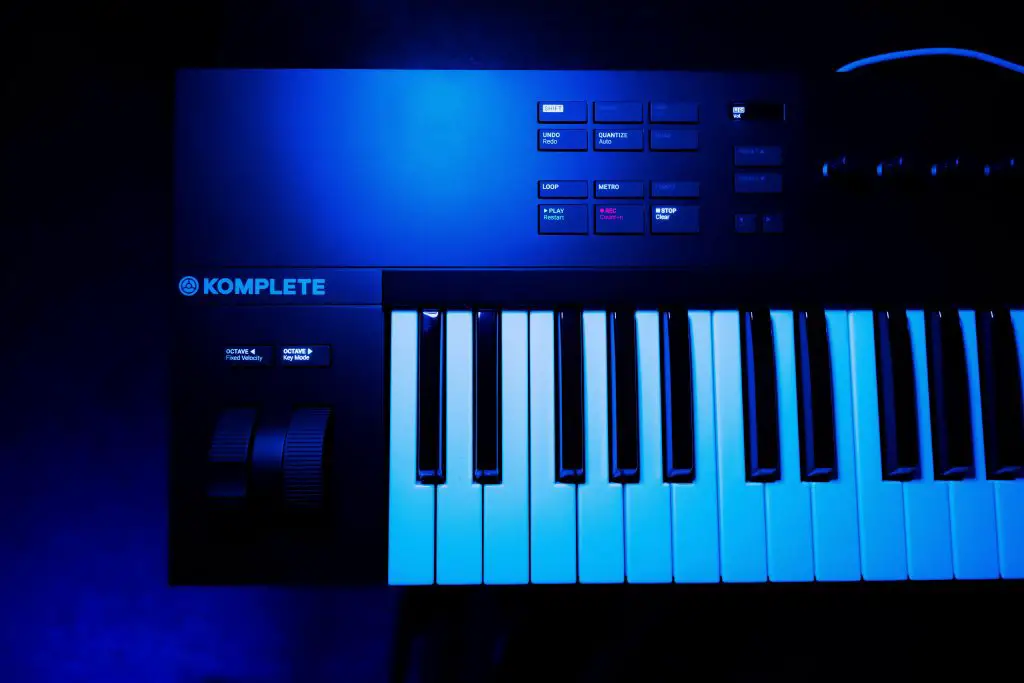 Image of a piano synthesizer inside a dark music studio. Source: pexels