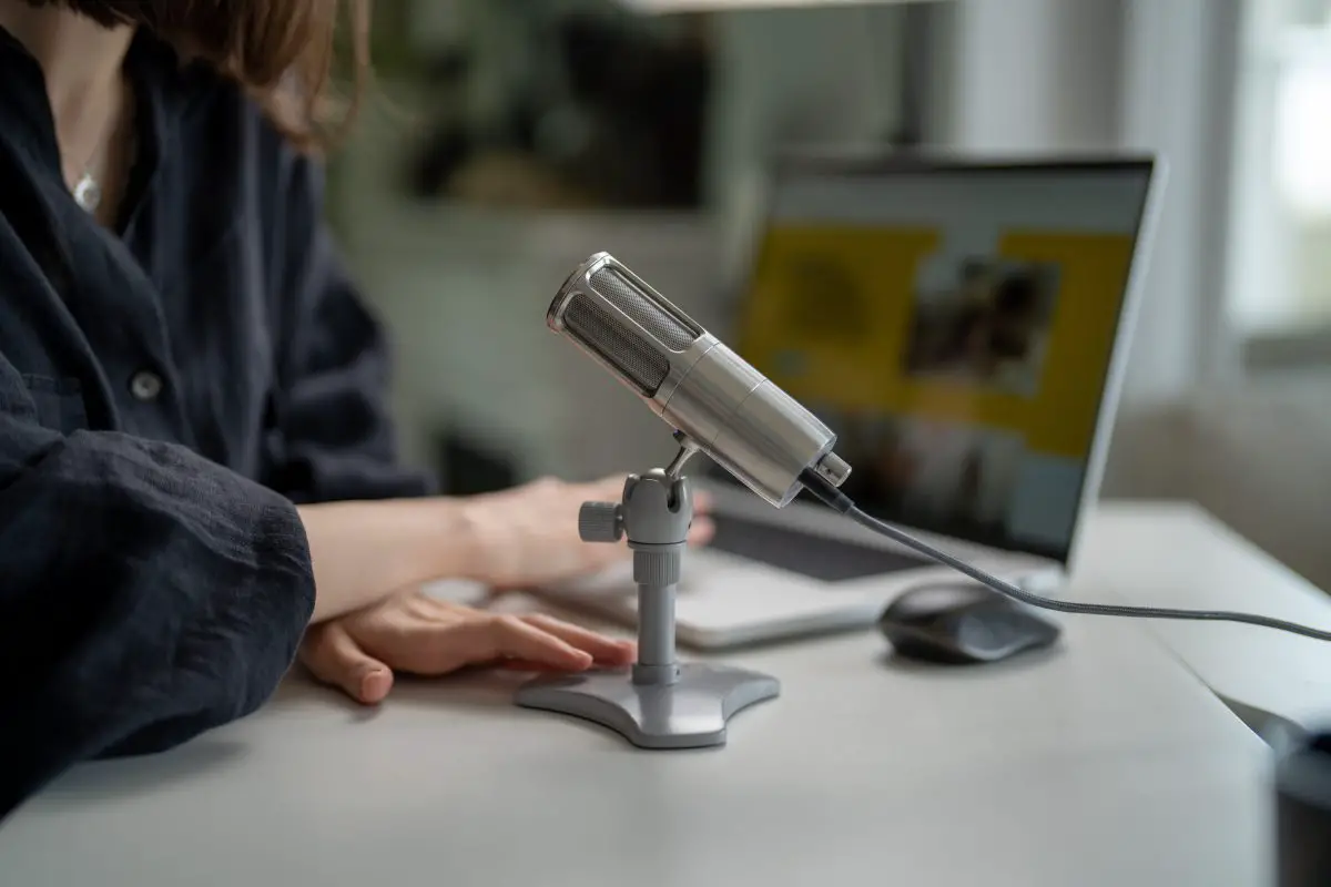 Image of a woman using usb microphone with mini stand on the table.