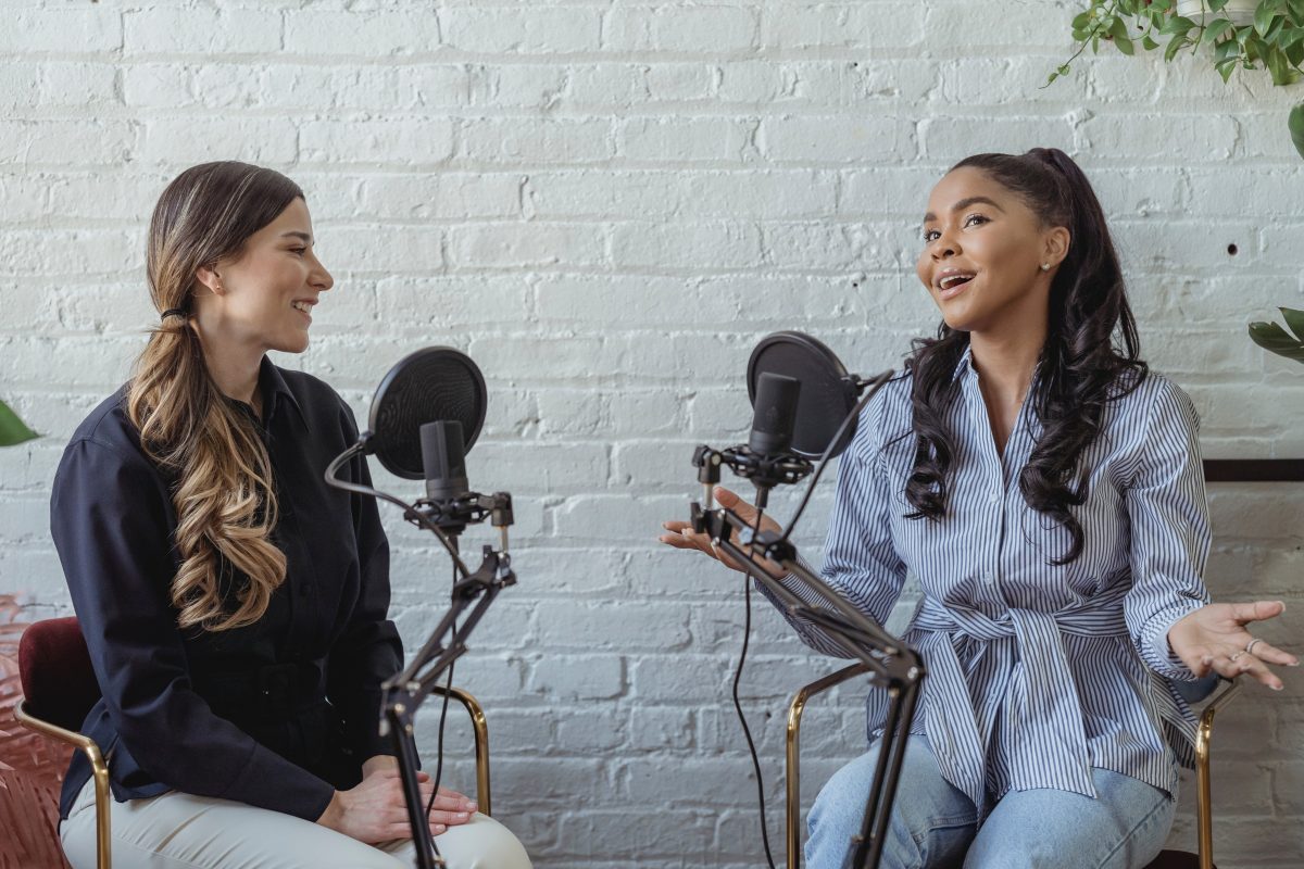 Image of two women talking in front of microphones.