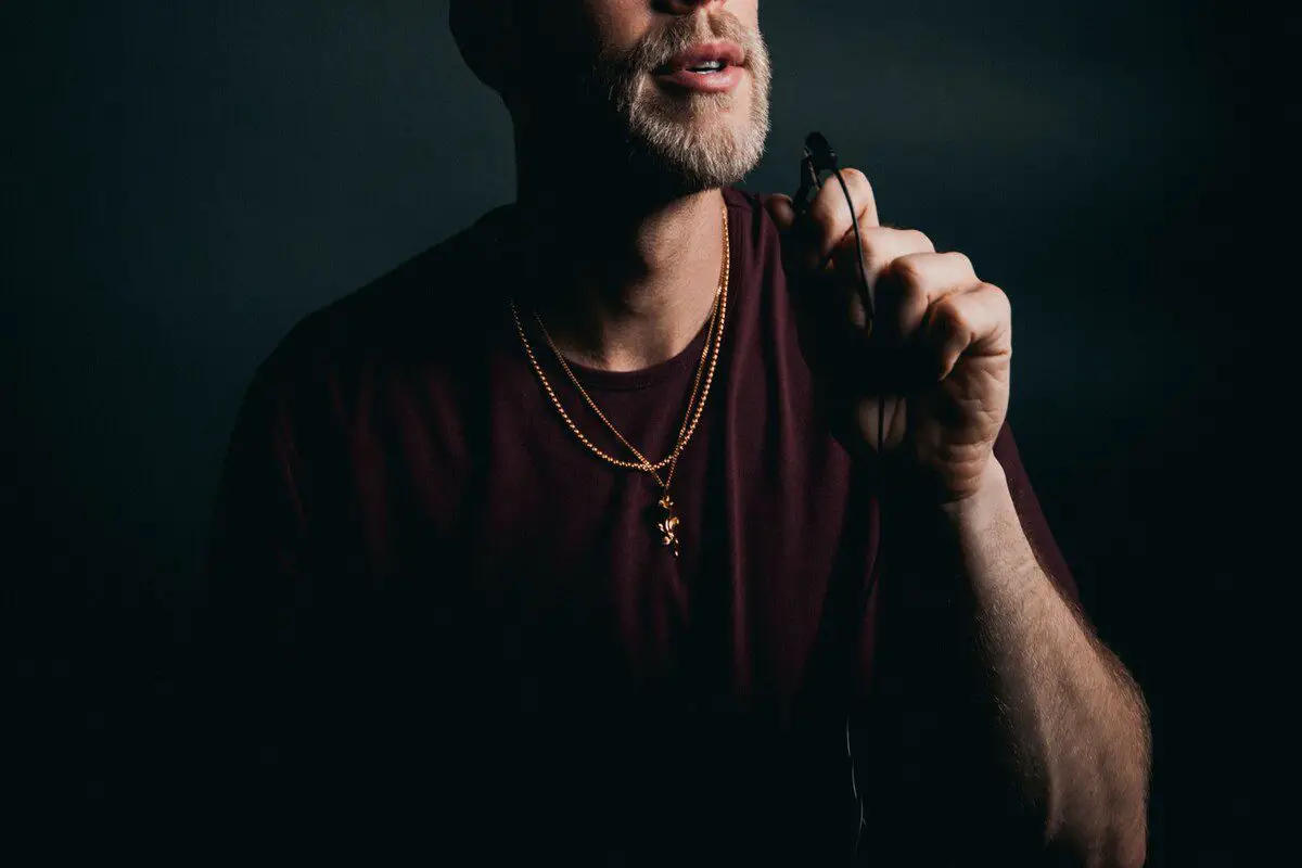 Image of a man holding a lavalier microphone near his mouth. Source: unsplash