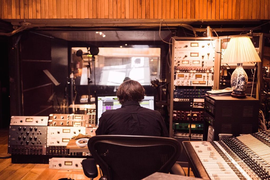 Image of a man in front of an audio mixer inside a studio. Source: unsplash