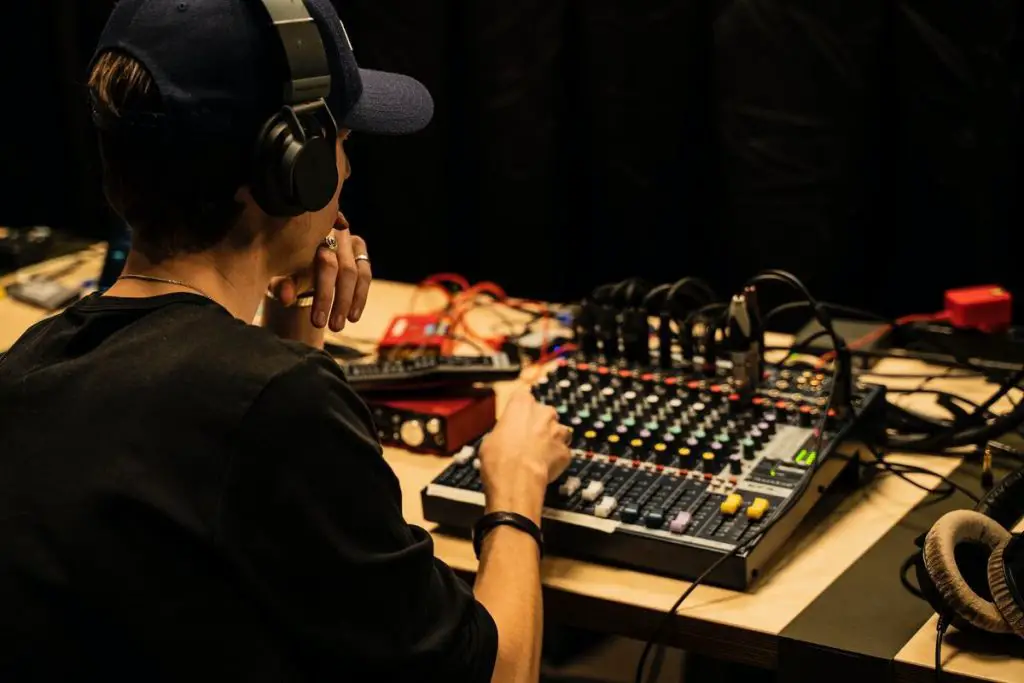 Image of a man with headphones on adjusting a mixer unsplash