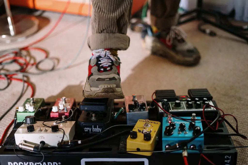 Image of a musician stepping on a pedal with cables on the floor pexels
